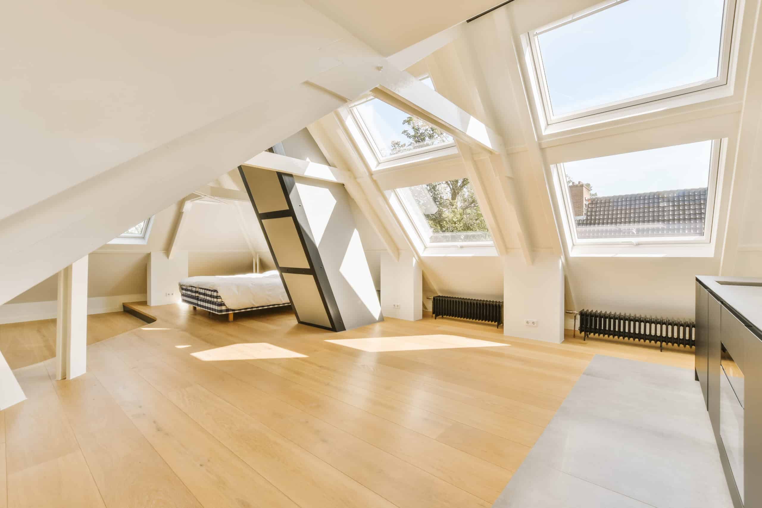 a large attic room with a bed and two windows